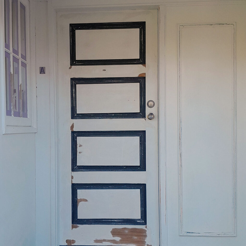 The image is of a white door with a black frame, which is a front door before painting. It's the exterior door of a home