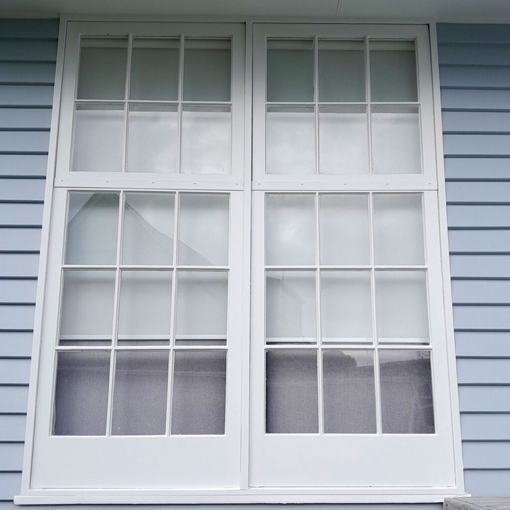 The image shows a window with a grid of smaller windows. It is part of a house, and has been painted.