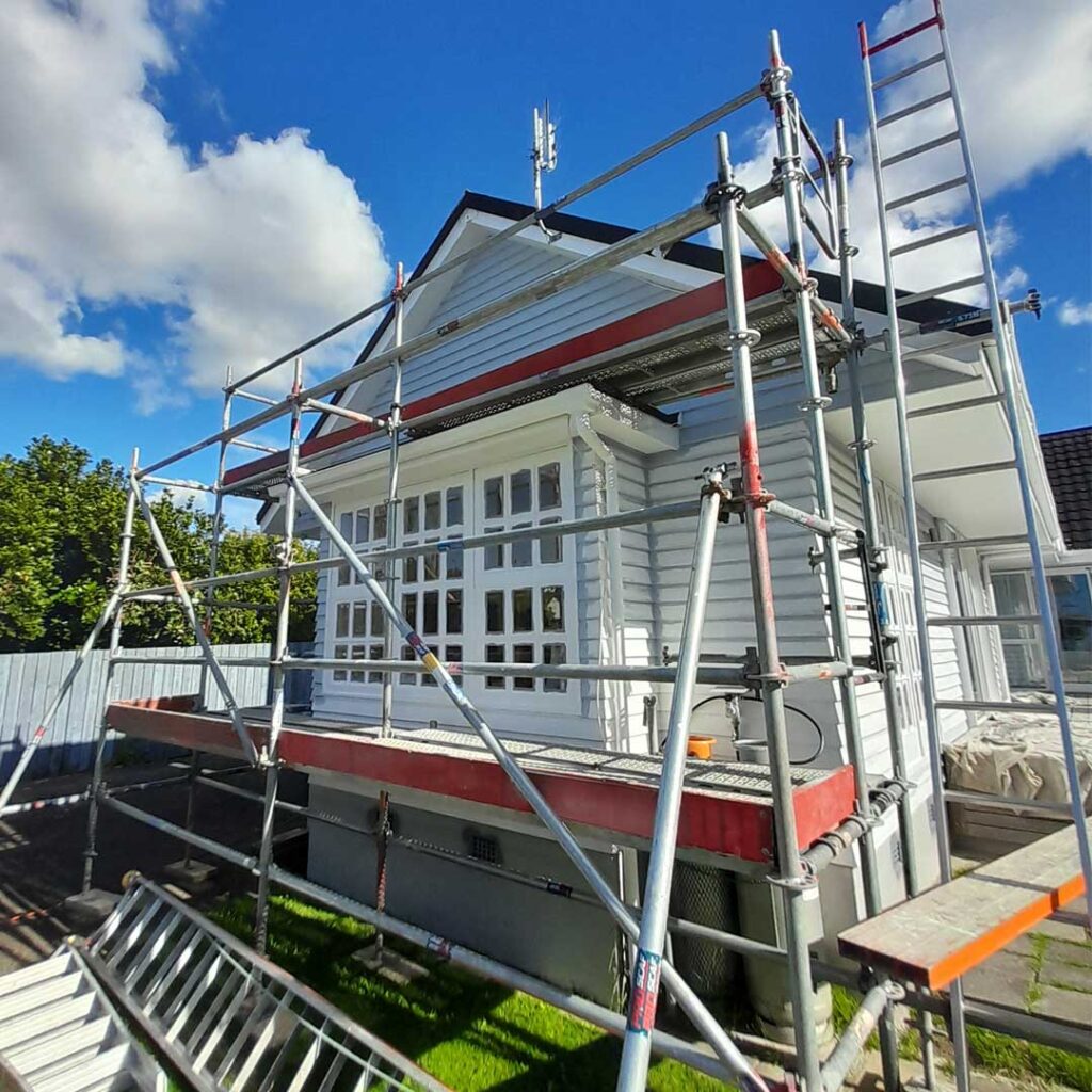 This image has blue sky, and features scaffolding used for house painting.