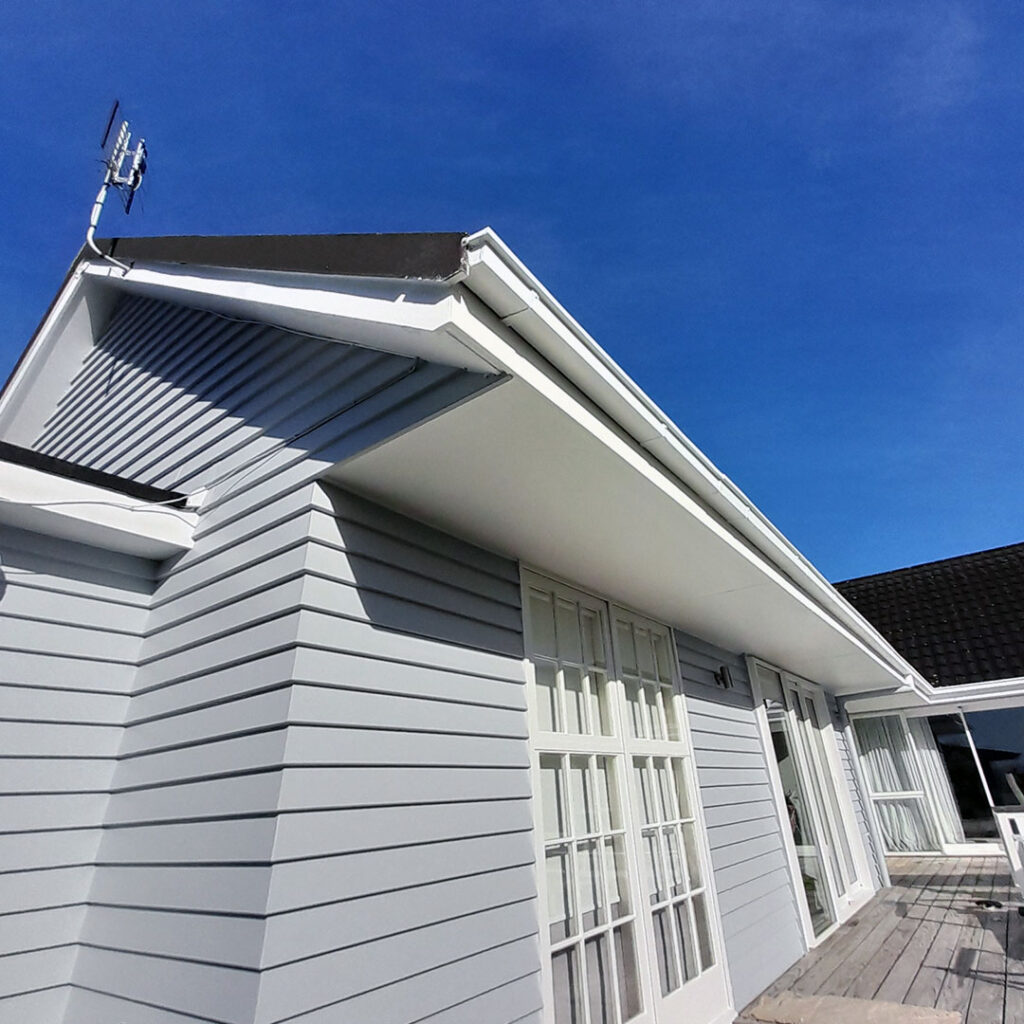 The image shows a newly painted home with white windows and blue sky.