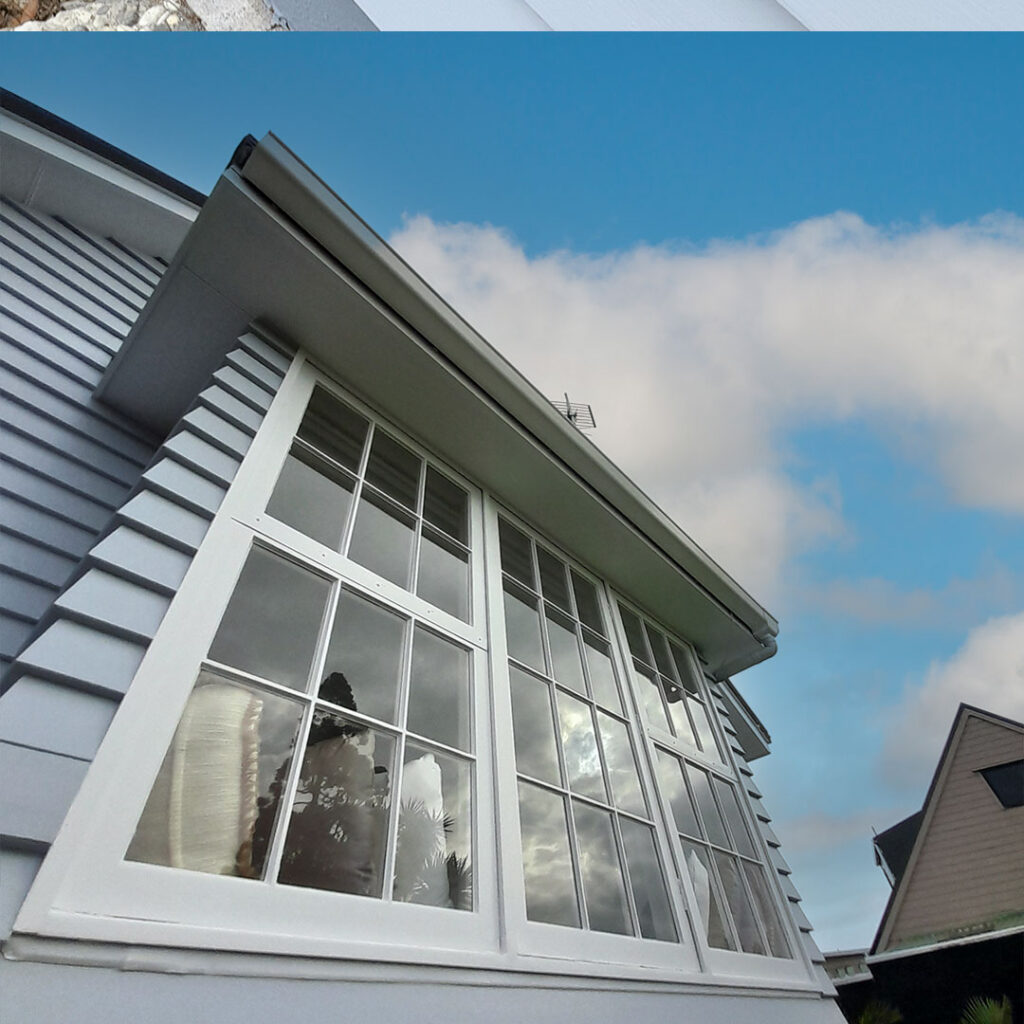 Grey weatherboards and white windows after being painted.