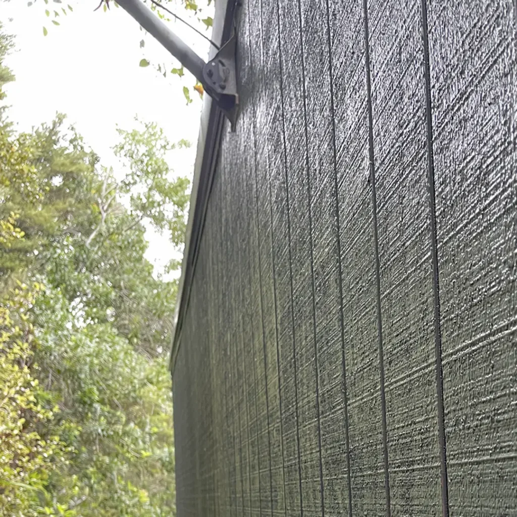 The image shows newly painted vertical cladding. In the background, there is a tree, outdoor setting, and a clear sky. The vertical cladding been painted using Weathershield® ColourGuard™ Rawene.