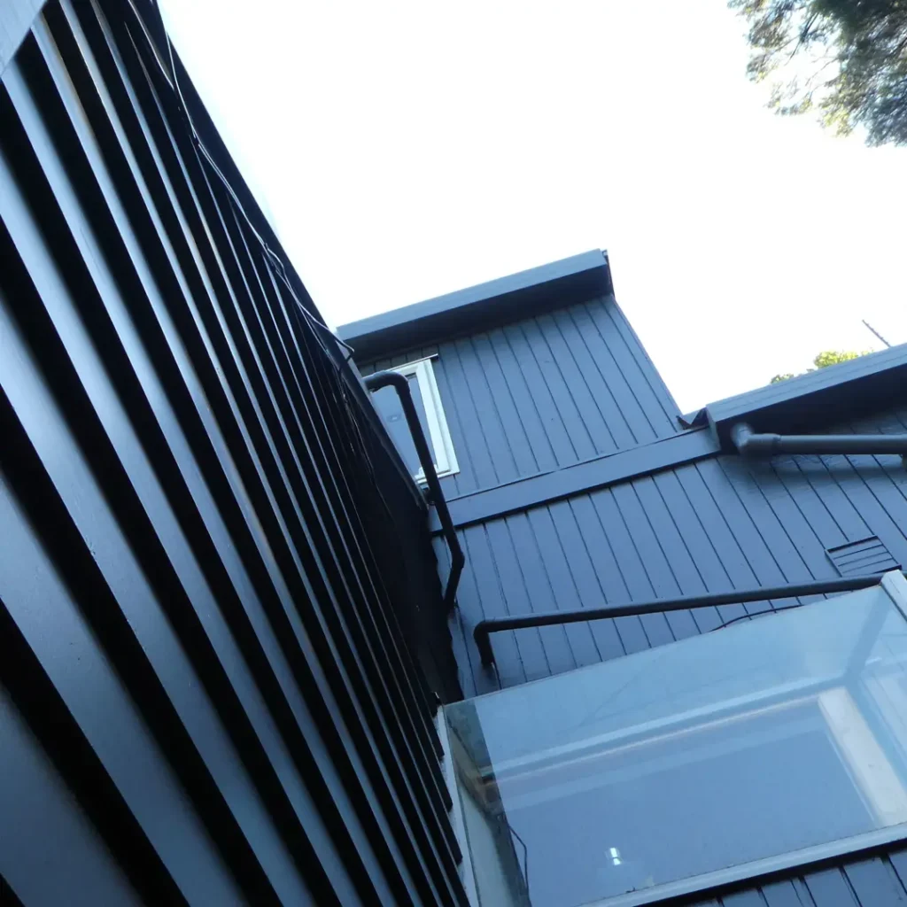 The image shows a building with recently painted vertical cladding. The building was painted using Weathershield® ColourGuard™ Rawene. The background includes a clear sky.