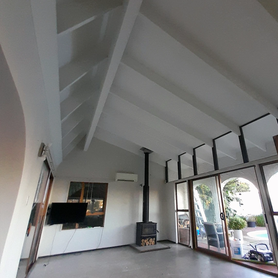 white painted beams with a fireplace and a pool outside